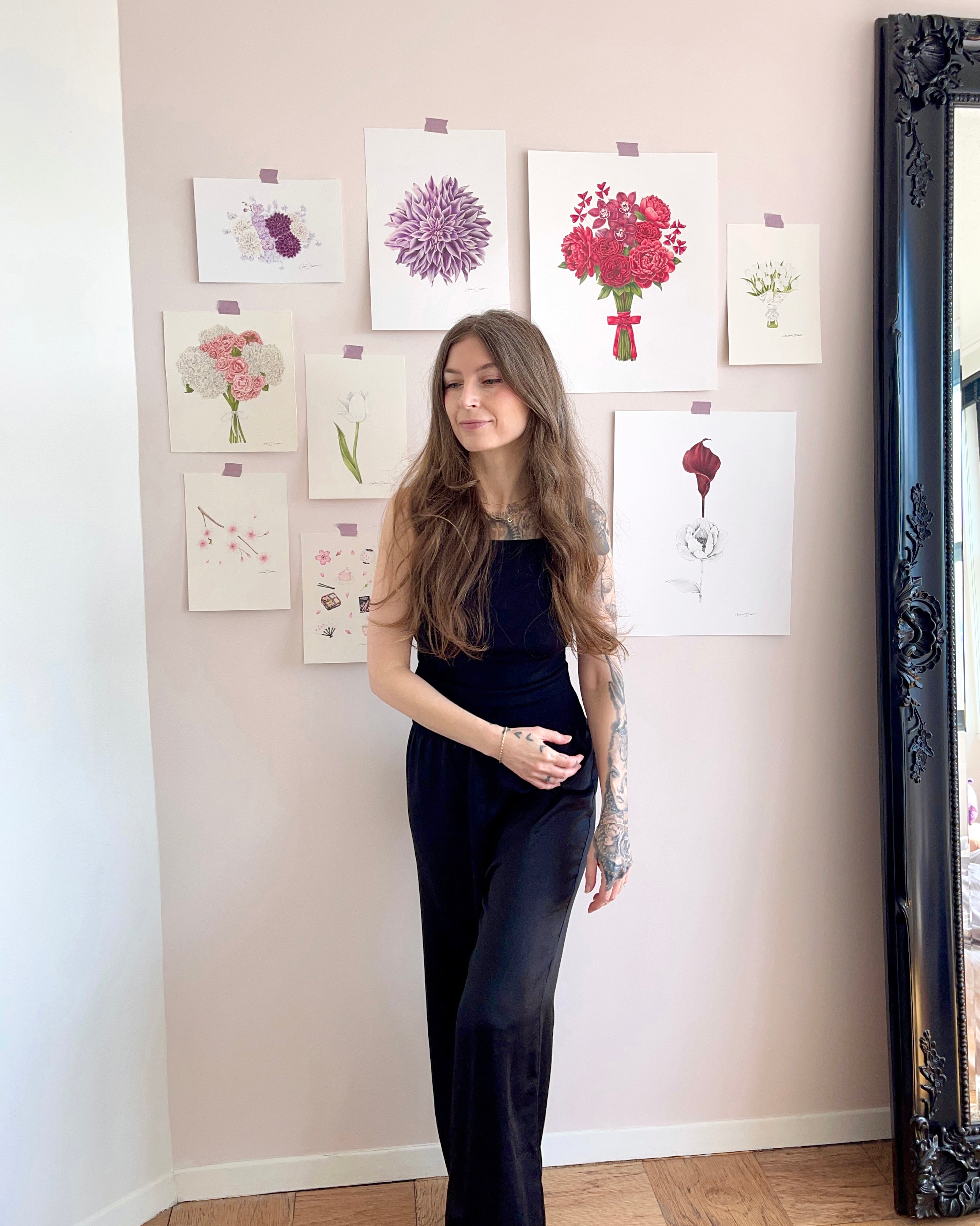The artist in front of her floral art on the wall.