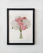 Framed artwork of a bouquet of pink and white flowers on a white wall.