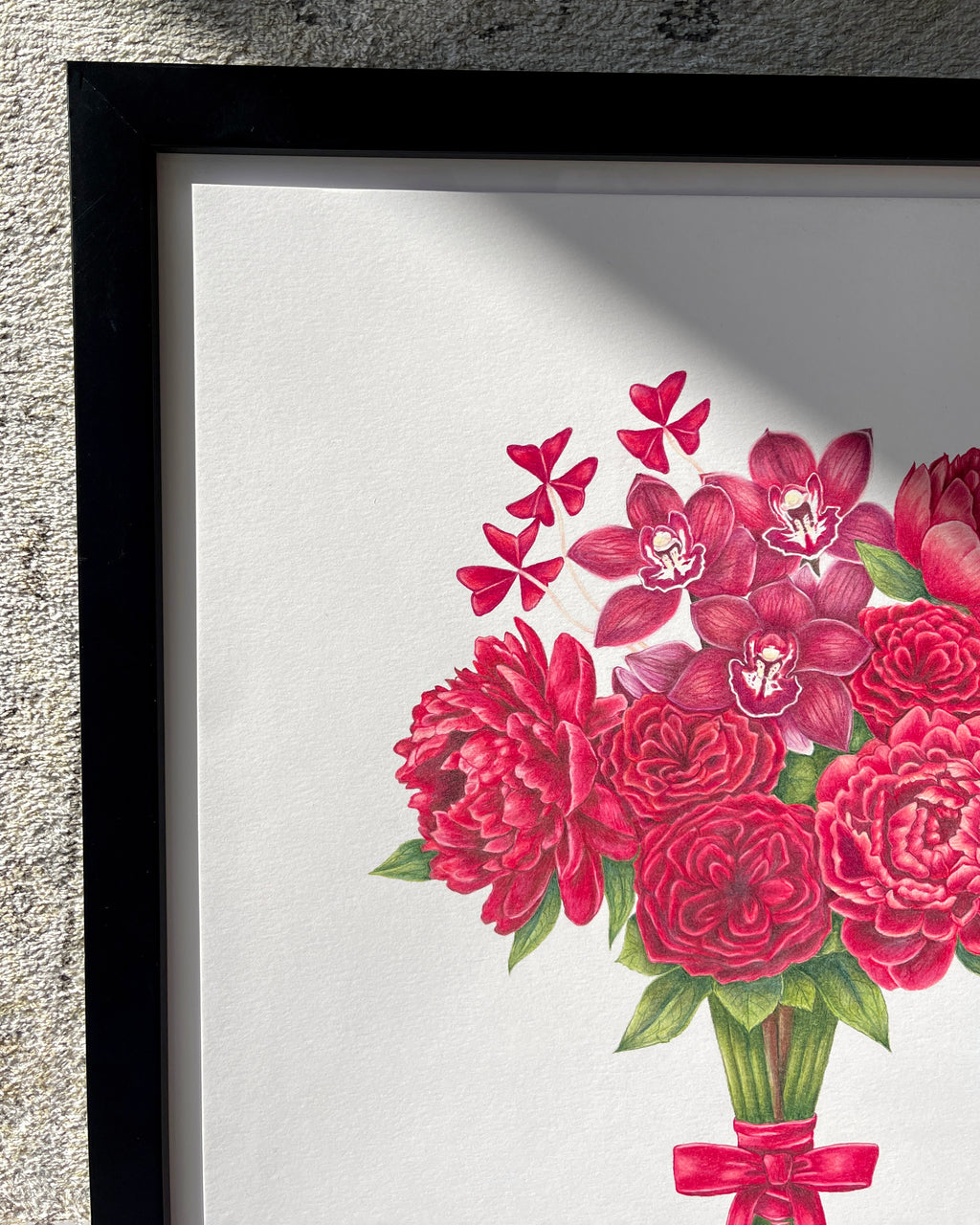 Framed artwork of red flowers with a black frame on a textured wall.