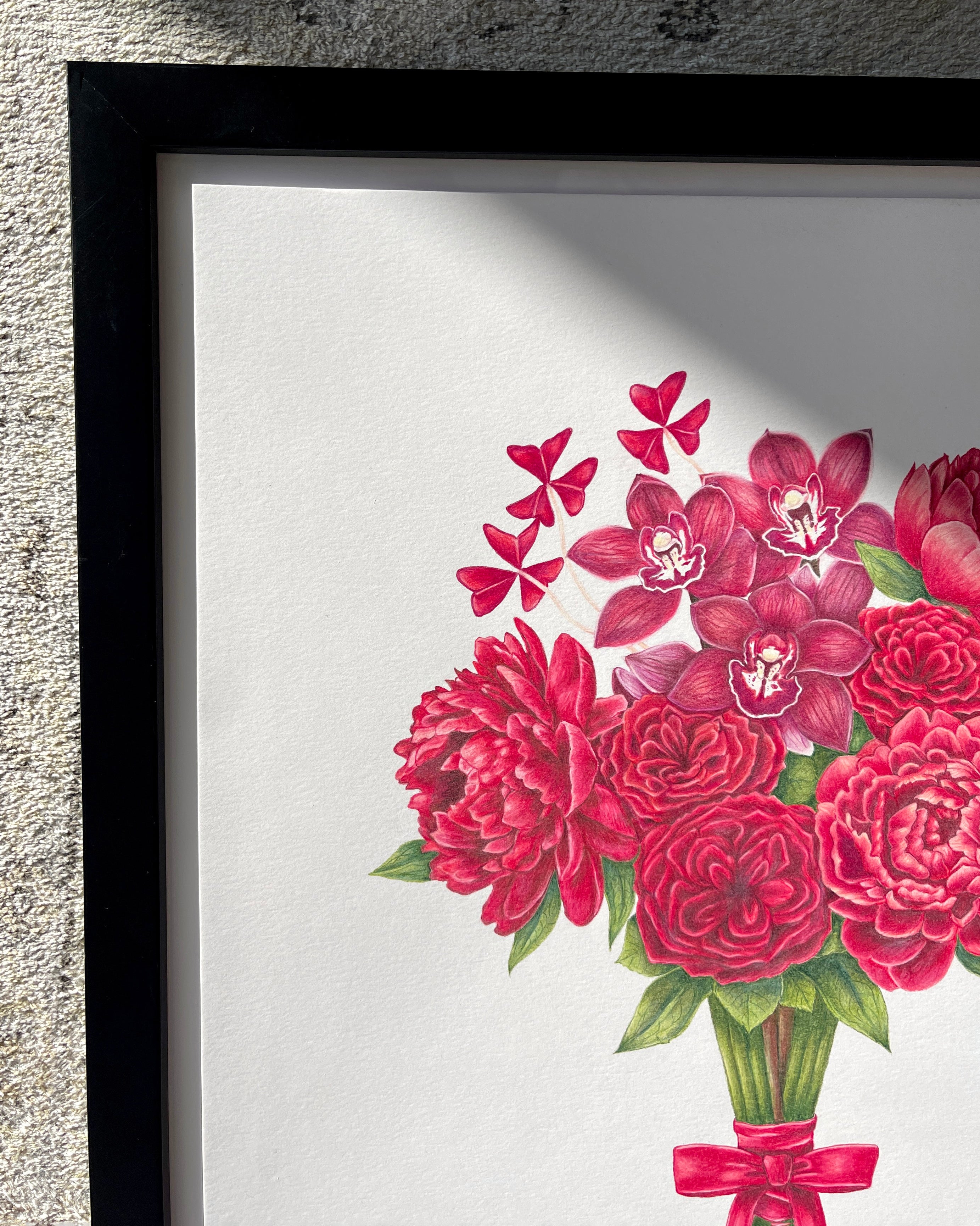 Framed artwork of red flowers with a black frame on a textured wall.