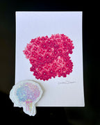 'The Bloom Edition August 2026' arranged on a black background. The edition includes a pink hydrangea art print and a pastel flower-shaped sticker