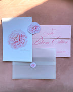 'The Bloom Edition September 2026' arranged on a blush background. The edition includes a blush envelope with pink script, a vellum sleeve with rose sticker seal, a pink rose art print, a rose-shaped sticker and printed studio note